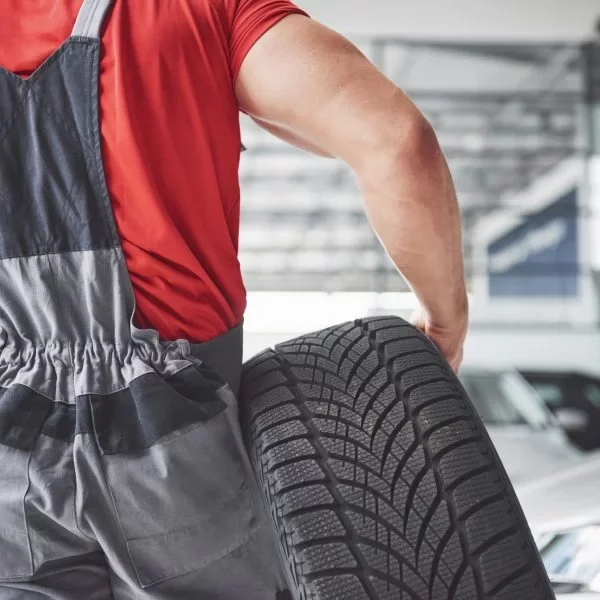 mechanic-holding-tire-tire-repair-garage-replacement-winter-summer-tires-scaled-q6vyimgrzwpljx6p513wxqf7eqo39en03c0gm34r5c